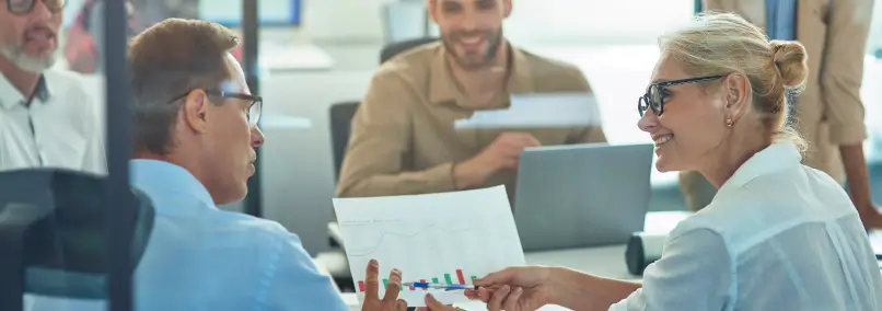 Coworkers smiling while going over data on a paper.