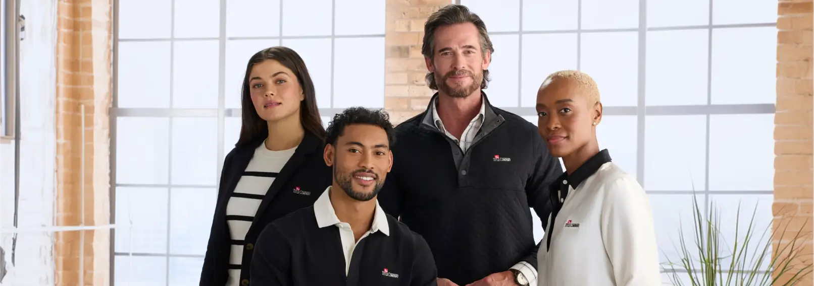 Four team members in coordinated branded apparel standing in a modern office
