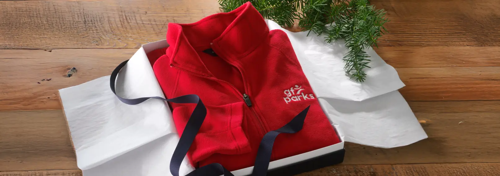 Gift box with black corporate gifts inside, sitting on cream colored fabric.