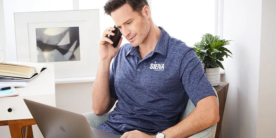 Two sailboats pass by a lighthouse on the coast.