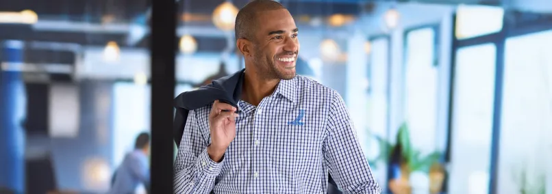 A professional man wearing a branded corporate uniform button-down shirt in a modern office.