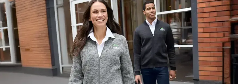 Man and woman in matching branded jackets, suitable for hybrid events.