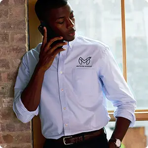 A man talking on a phone wearing a button down dress shirt.