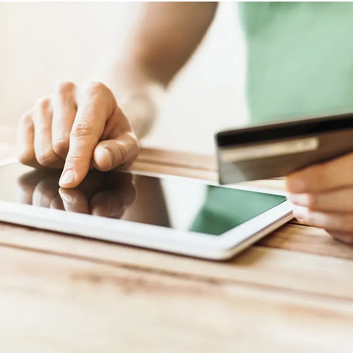 A person using a credit card to pay on a tablet.