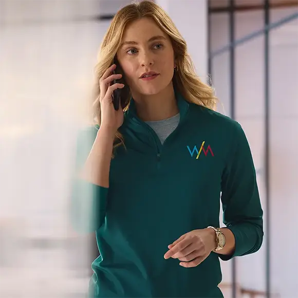An employee taking a phone call wearing a green quarter-zip.