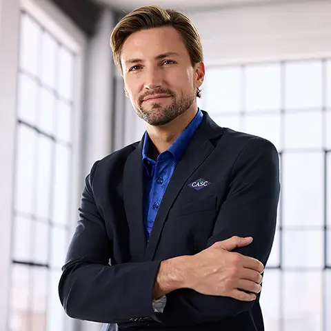 A man weaering a blazer over a blue polo.