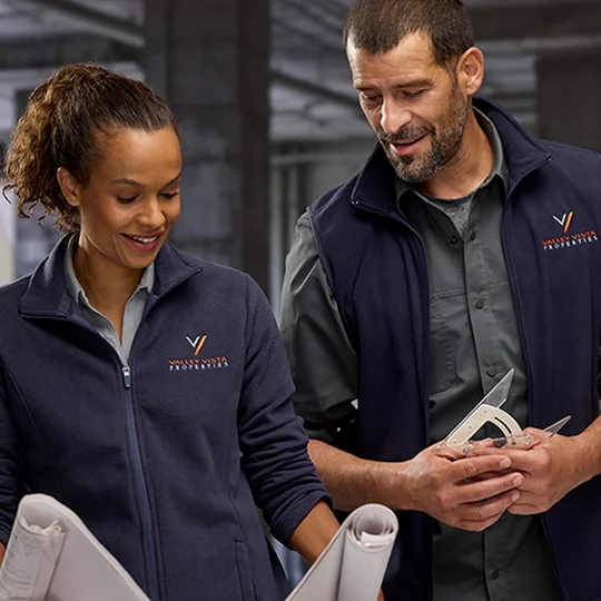 Woman wearing a blue fleece jacket and man wearing a blue fleece vest.