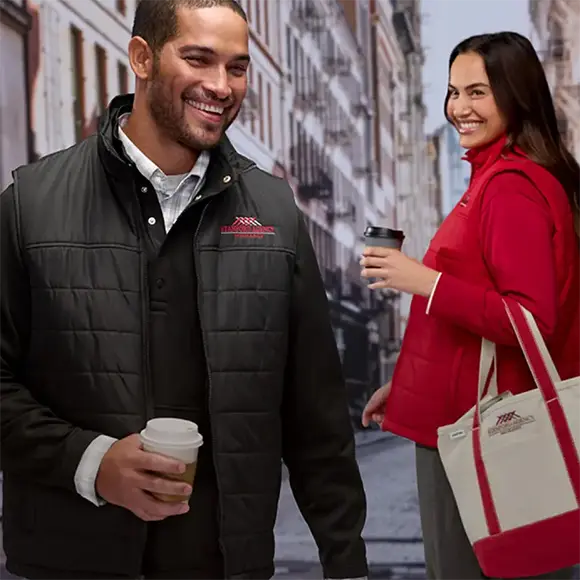Two employees wearing a jackets and drinking coffee.