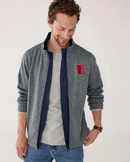 A man wearing a gray jacket with custom logo embroidery.