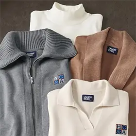 Four different sweaters in neutral colors laid on top of each other.