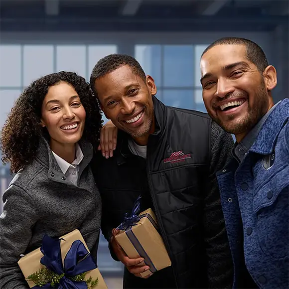 Three employees exchange gifts.
