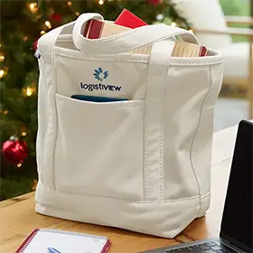 A tote bag filled with gifts near a Christmas tree.
