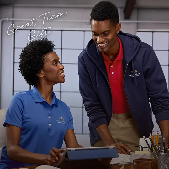 Great Team Gift! Two employees wearing active polo shirts lean over a desk.