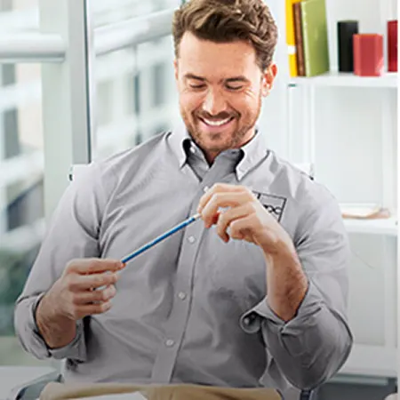 A man wearing a dress shirt holding a pencil.