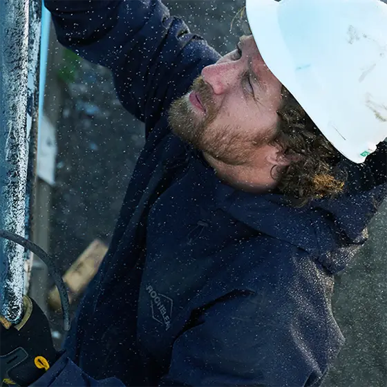 A man wearing a white hard hat doing physical labor.