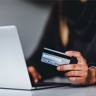 A person holding a credit card at a laptop.